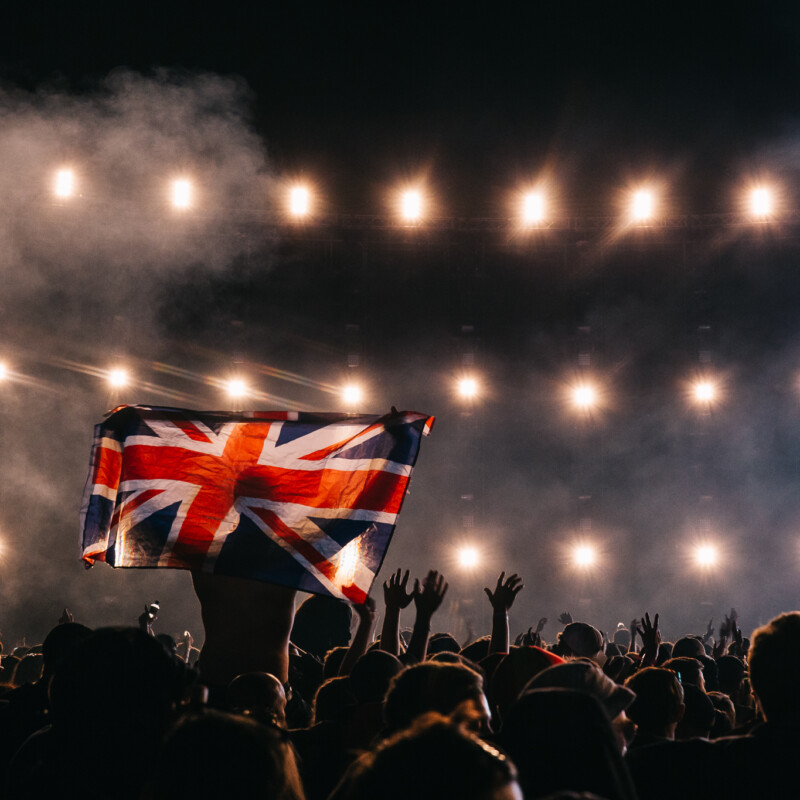 crowd in darkness with a fan holding up a Union Jack flag